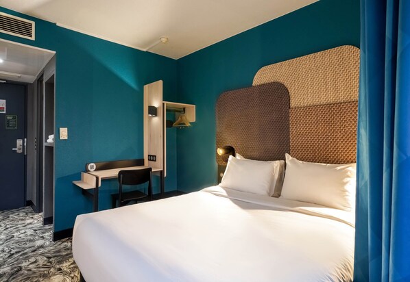 A hotel room with a large bed, a desk, a chair, a wardrobe, and a mirror. - B&B HOTEL Paris Châtillon (Chatillon)