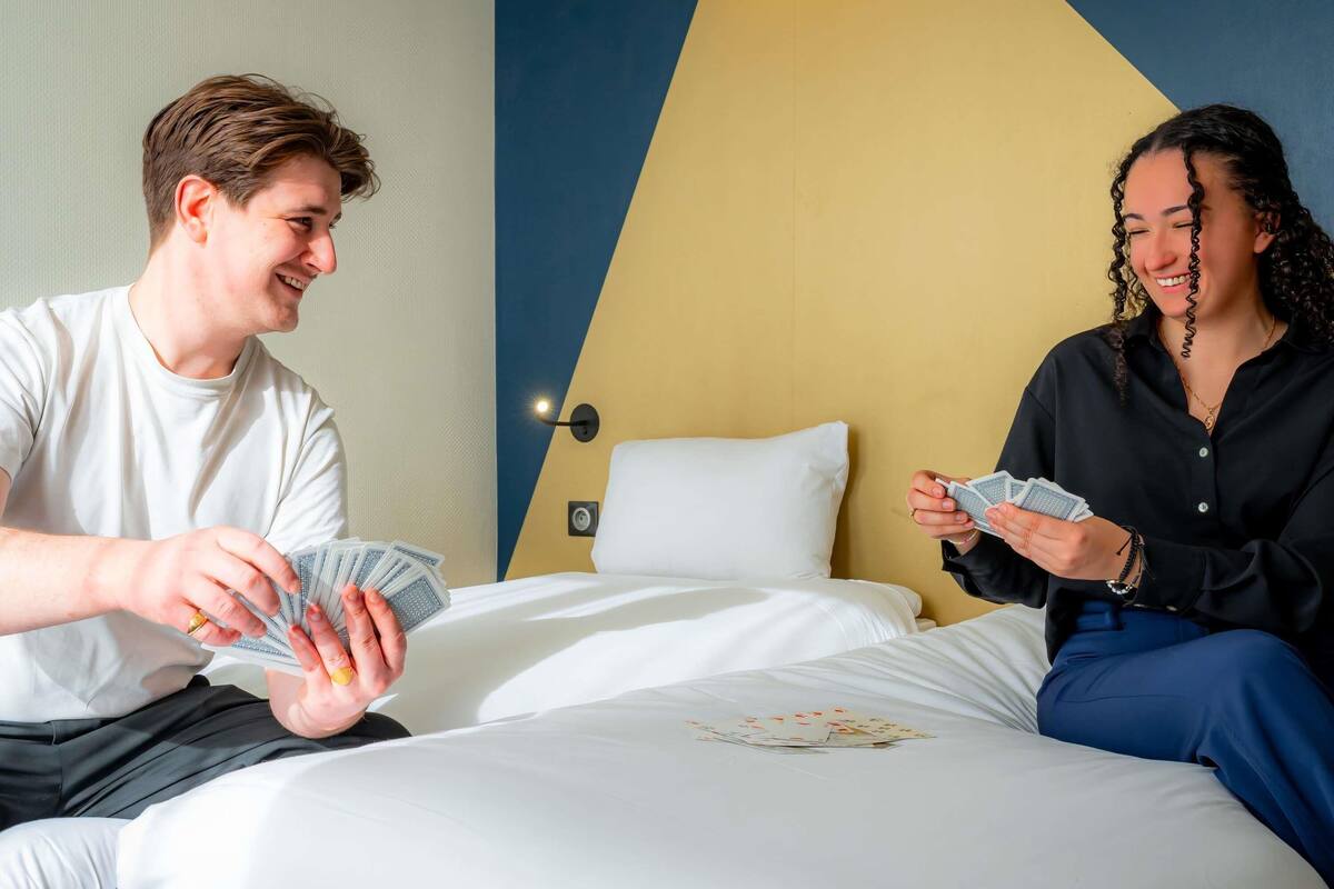 A hotel room with a bed, a nightstand, and a wall with a geometric design.