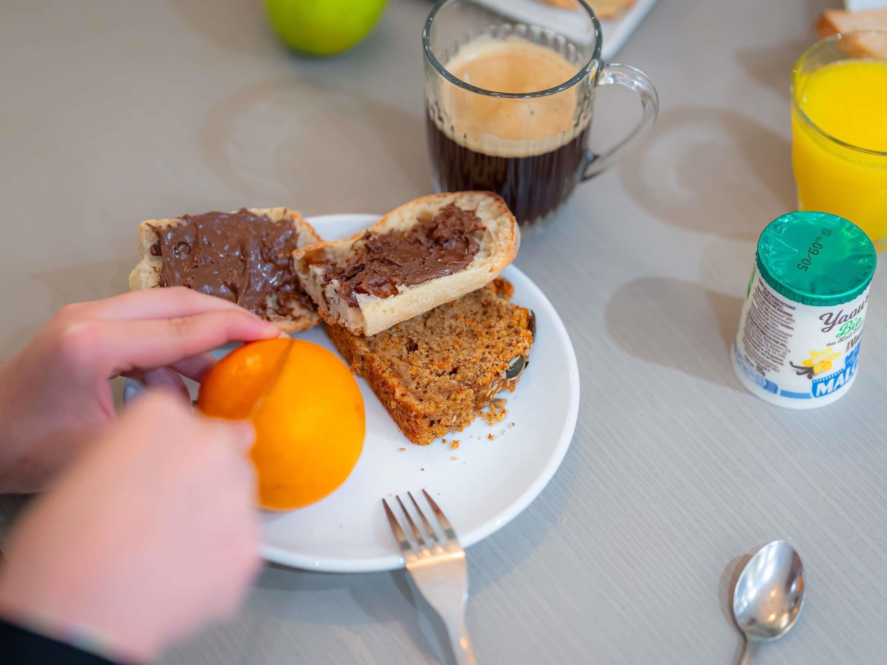 A breakfast setting with a plate of toast, a glass of coffee, a glass of orange juice, and a bottle of milk.