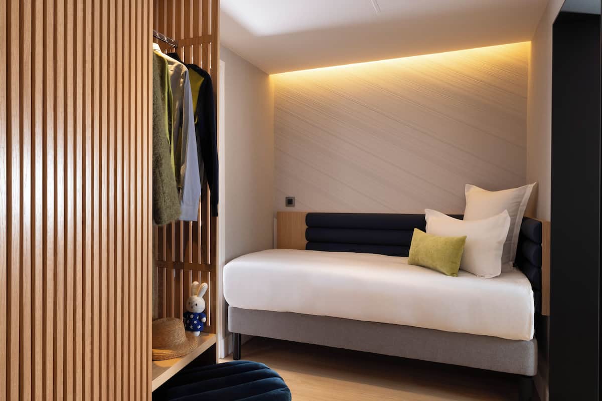 A modern bedroom with a bed, a wardrobe, and a shelf with a decorative item.