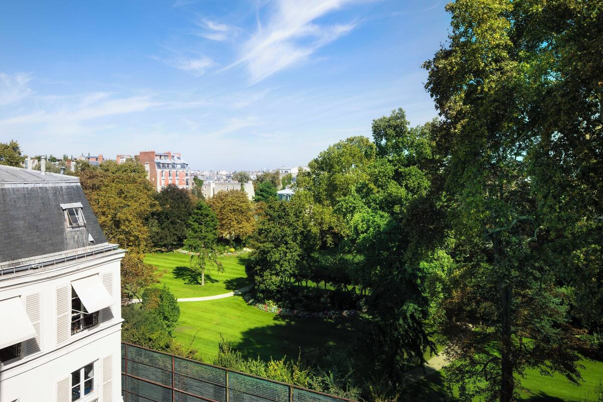 A residential building with a view of a park and distant cityscape.