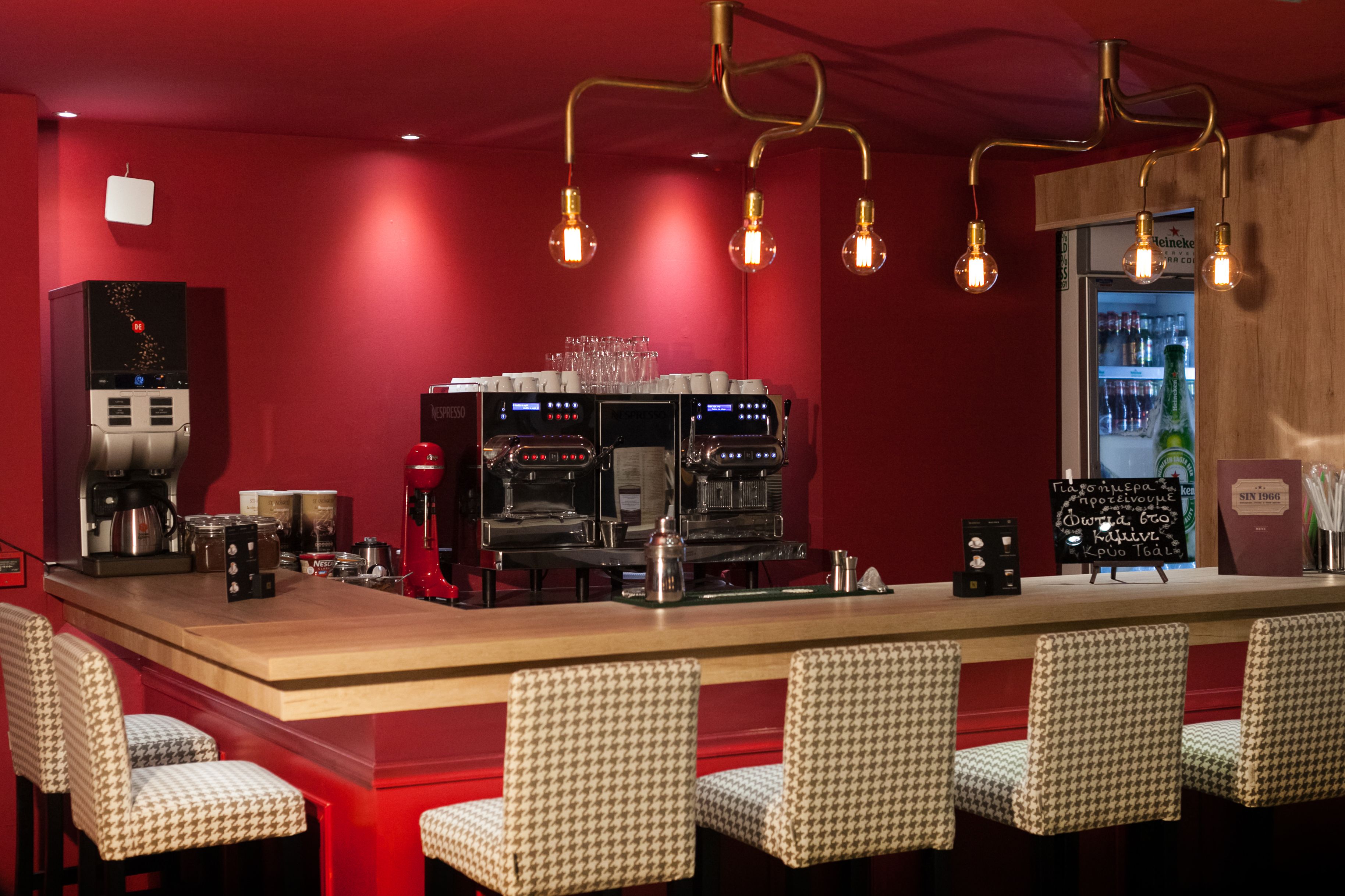 Baarialue, jossa on espressokoneita, juomia sisältävä jääkaappi ja ruutukuviolliset tuolit.