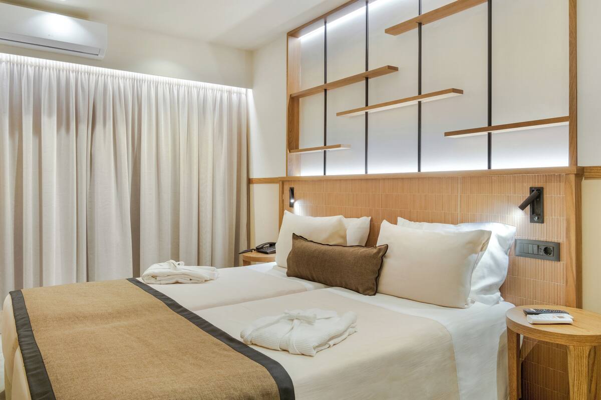 Ein Hotelzimmer mit einem großen Bett, einem Nachttisch mit Telefon und einer Wandleuchte.