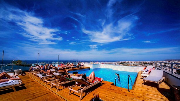 A poolside area with sun loungers and a pool, overlooking a cityscape. - Capsis Astoria Heraklion Hotel (Heraklion)
