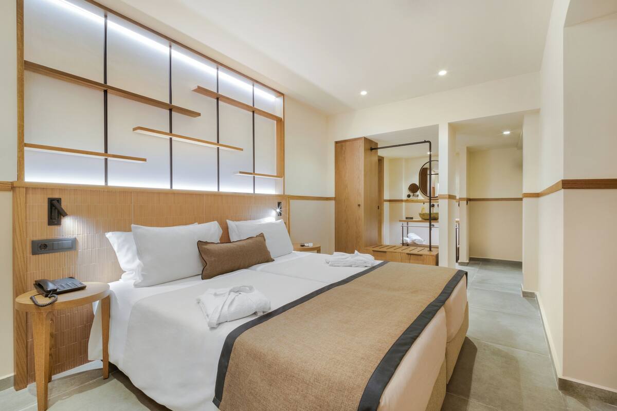 Ein Hotelzimmer mit einem großen Bett, Nachttischen, einem Spiegel und einem Holzkopfteil.