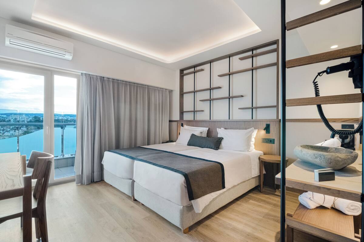 Ein modernes Hotelzimmer mit einem großen Bett, Blick auf die Stadt und einem Balkon.