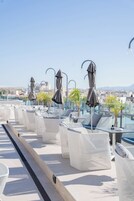 Μια ταράτσα με υπαίθριο χώρο και ομπρέλες, από την οποία μπορεί κανείς να θαυμάσει την πανοραμική θέα της πόλης.
