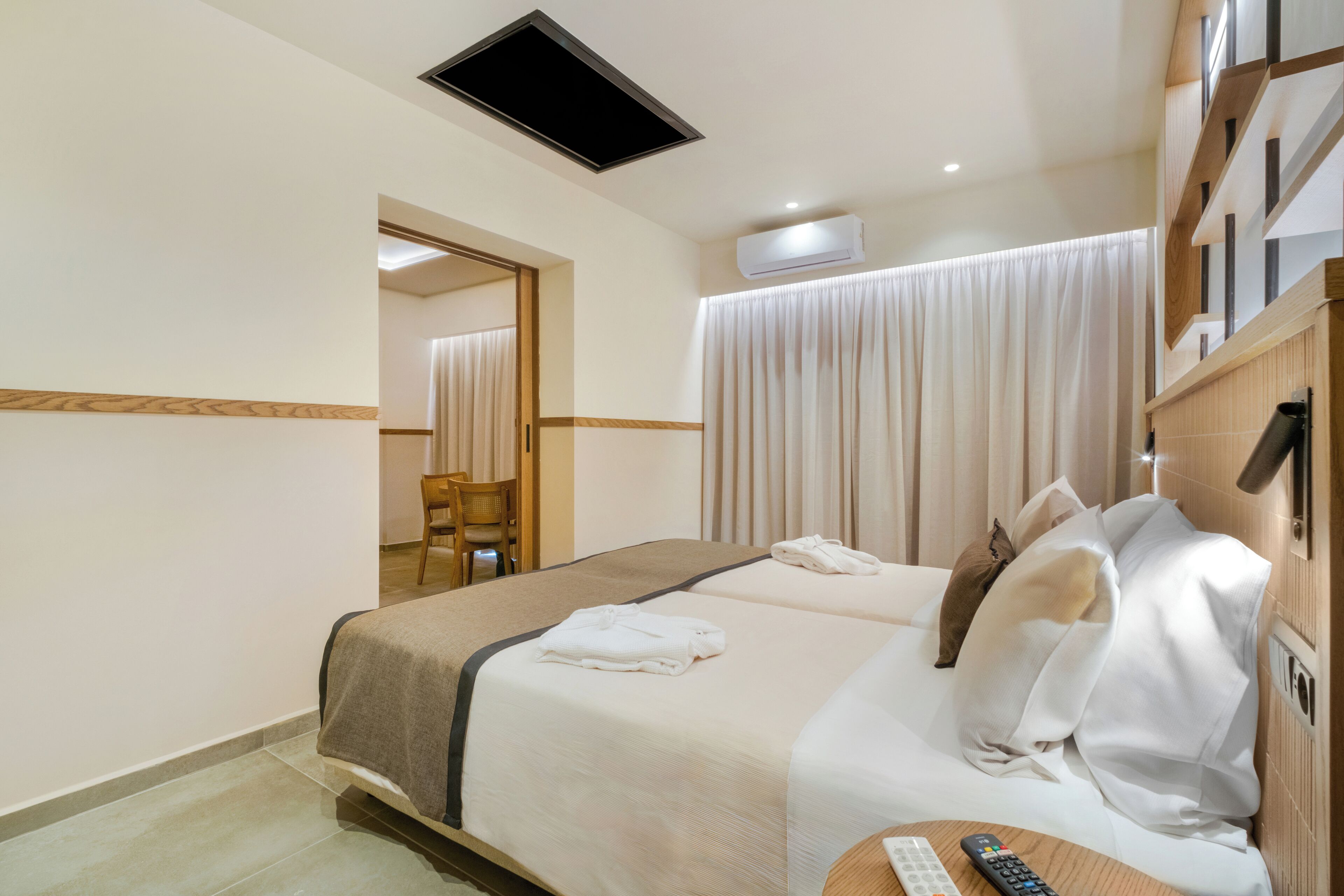 A hotel room with a bed, a chair, a desk, and a window with curtains.