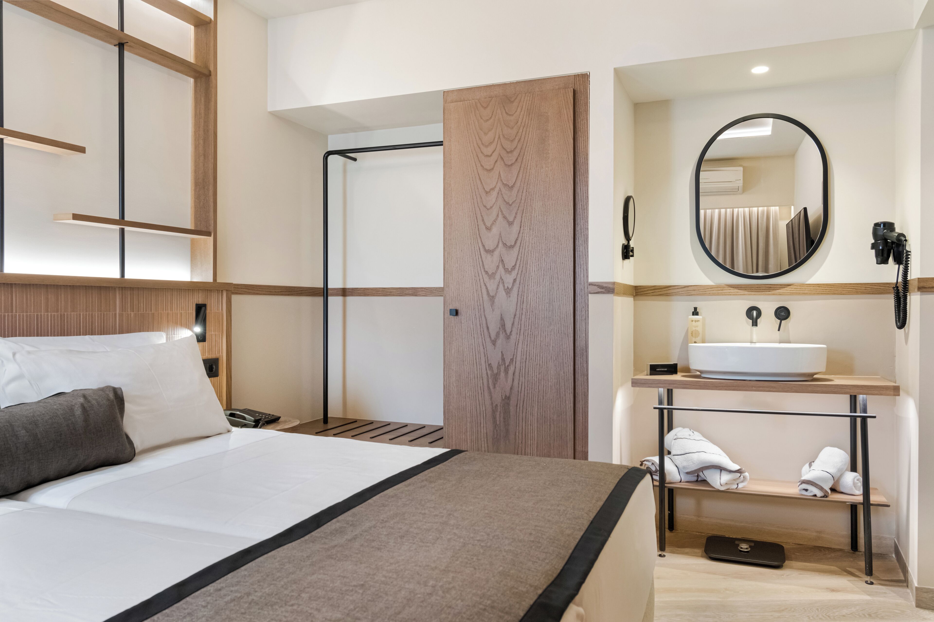 Una habitación de hotel con cama, baño con lavabo y espejo.