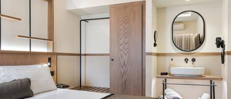 Una habitación de hotel con cama, baño con lavabo y espejo.