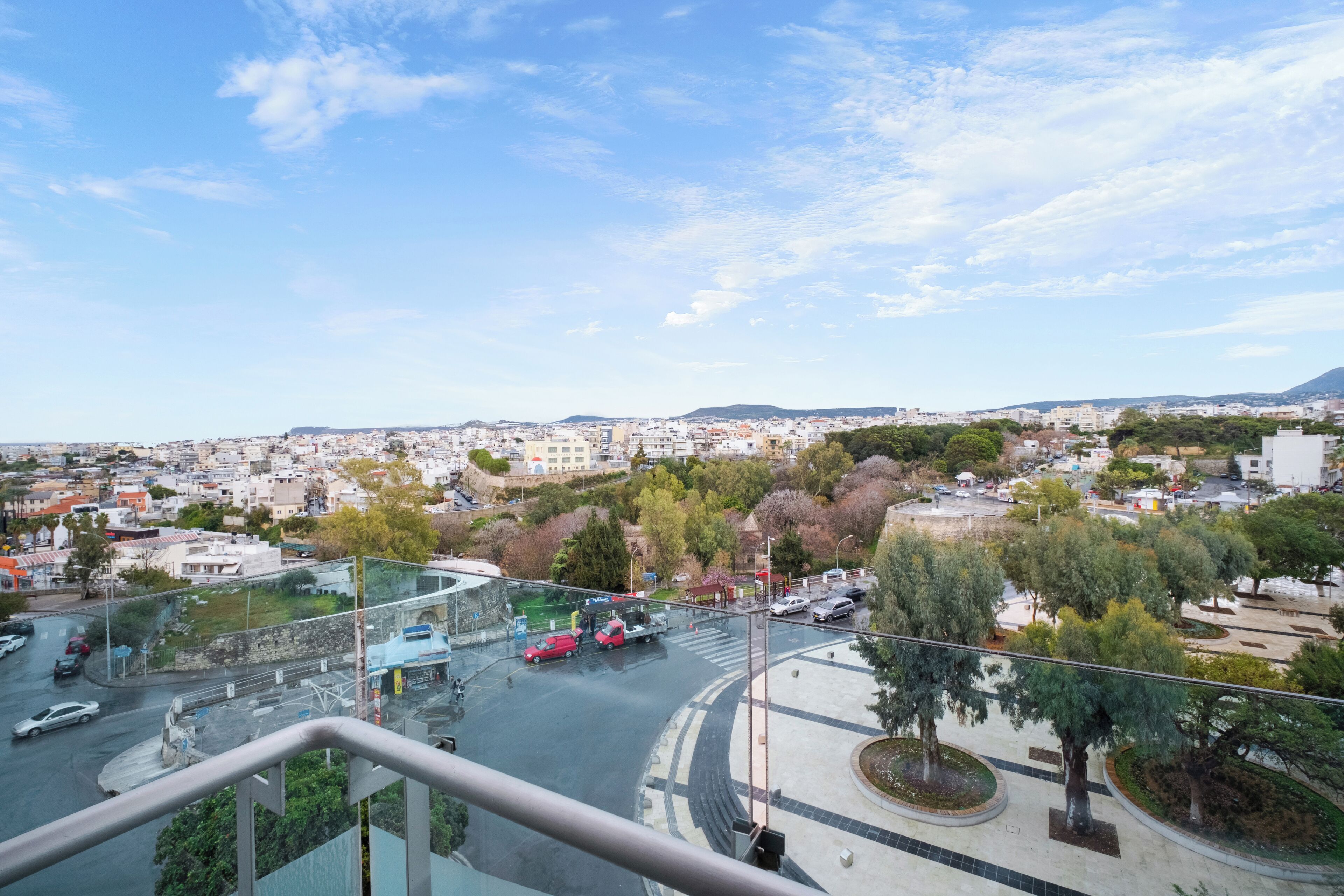 A cityscape with a view of a roundabout, buildings, and trees.