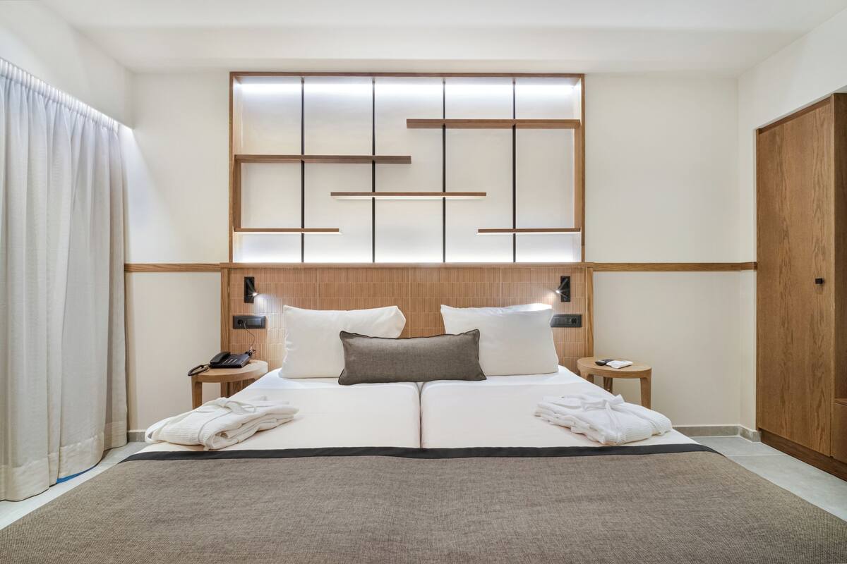 Ein Hotelzimmer mit einem großen Bett, einem Holzkopfteil, Nachttischen und einem Kleiderschrank.