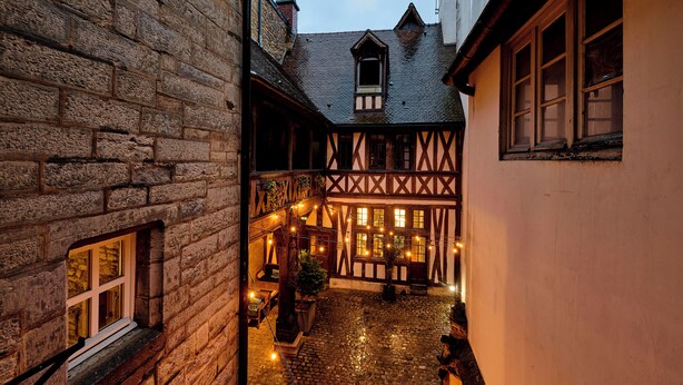 A narrow cobblestone alley with traditional half-timbered buildings on either side, a small window with a view, and a statue in the center. - Hôtel Philippe le Bon (Dijon)