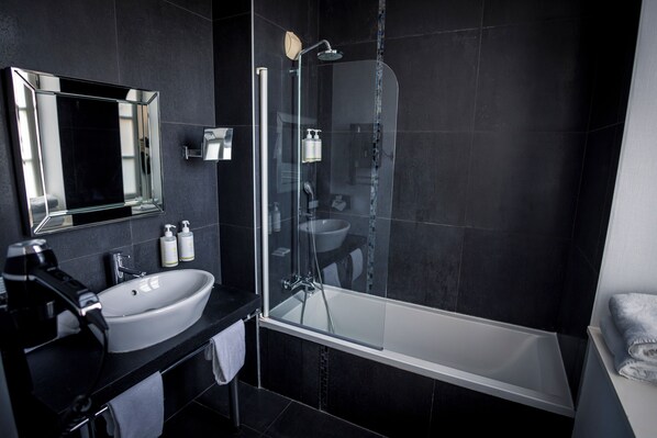 A modern bathroom with a large white sink, a glass-enclosed shower, and a bathtub.