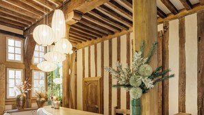 A reception area with a wooden reception desk, white chairs, and a large vase with flowers. - Hôtel Philippe le Bon (Dijon)