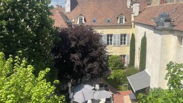 Une cour intérieure dotée d’un espace pour s’asseoir, entourée d’arbres et de bâtiments aux toits recouverts de tuiles rouges.