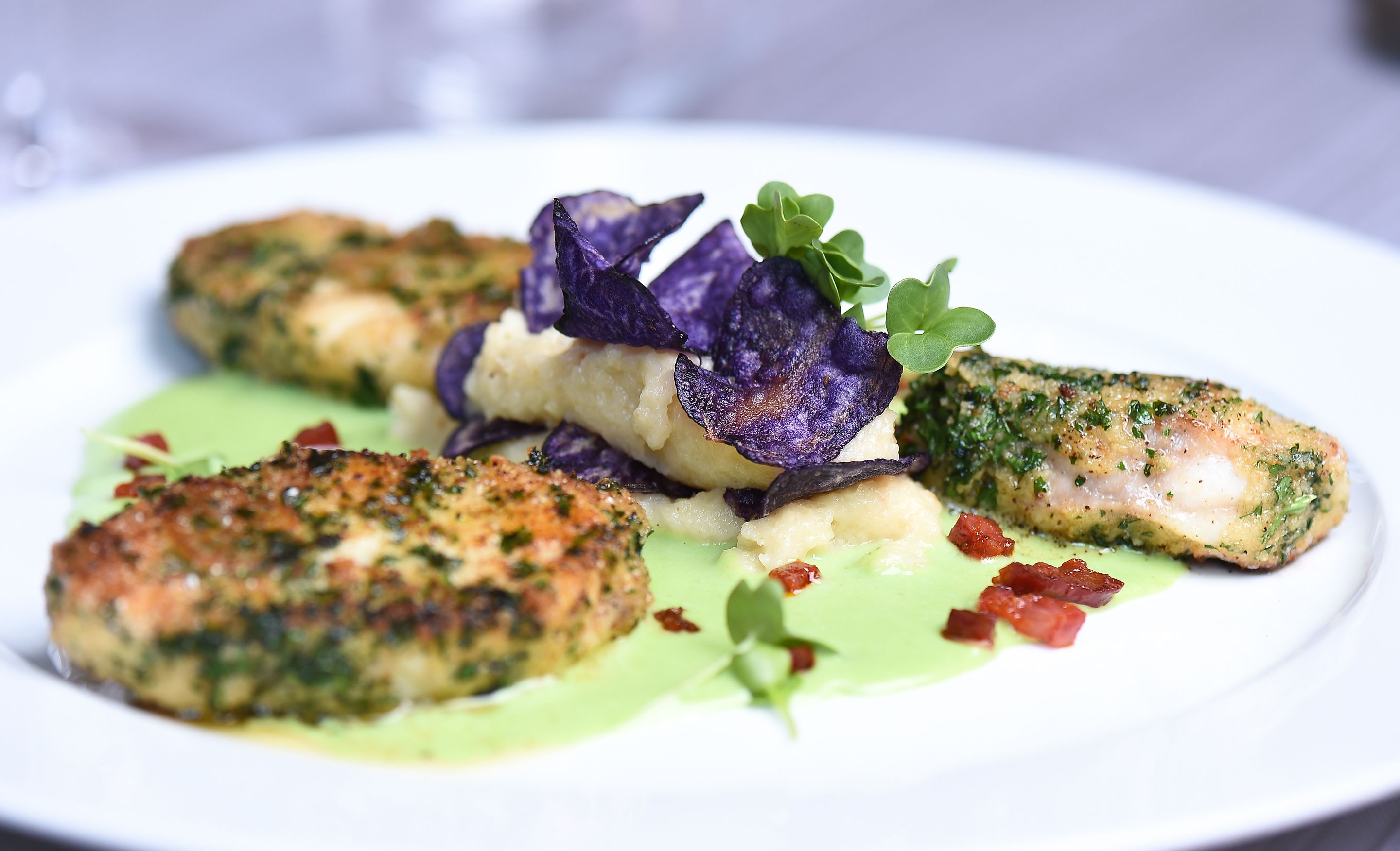 Un plato de comida con pescado, papas y verduras.