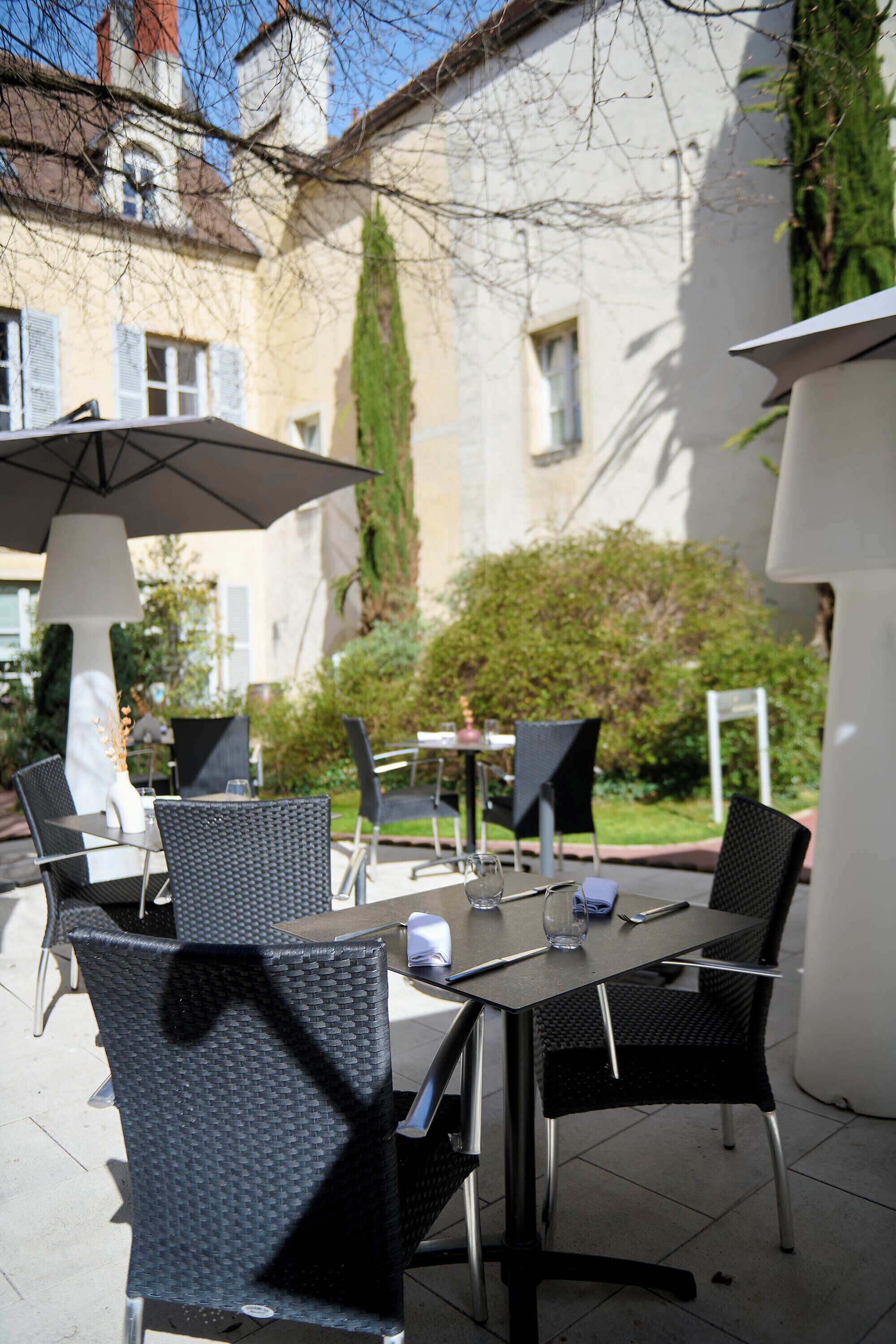Un espace extérieur aménagé pour les repas, avec des tables et des chaises, une lampe et un bâtiment en arrière-plan.