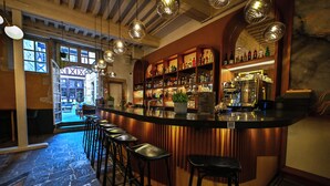A bar area with stools, shelves of bottles, and a counter. - Hôtel Philippe le Bon (Dijon)