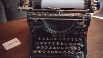 Une machine à écrire Underwood ancienne, posée sur une table en bois, avec une feuille de papier et un stylo à proximité.