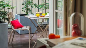 Un espacio exterior acogedor con una silla y una mesa, rodeado de plantas y una terraza de madera.