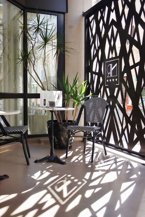 A modern indoor seating area with a table, chairs, and a decorative partition. - Hotel Nice Riviera (Nice)