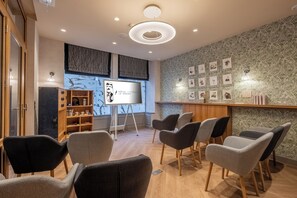 A conference room with modern chairs, a projector screen, and a wooden cabinet with shelves.