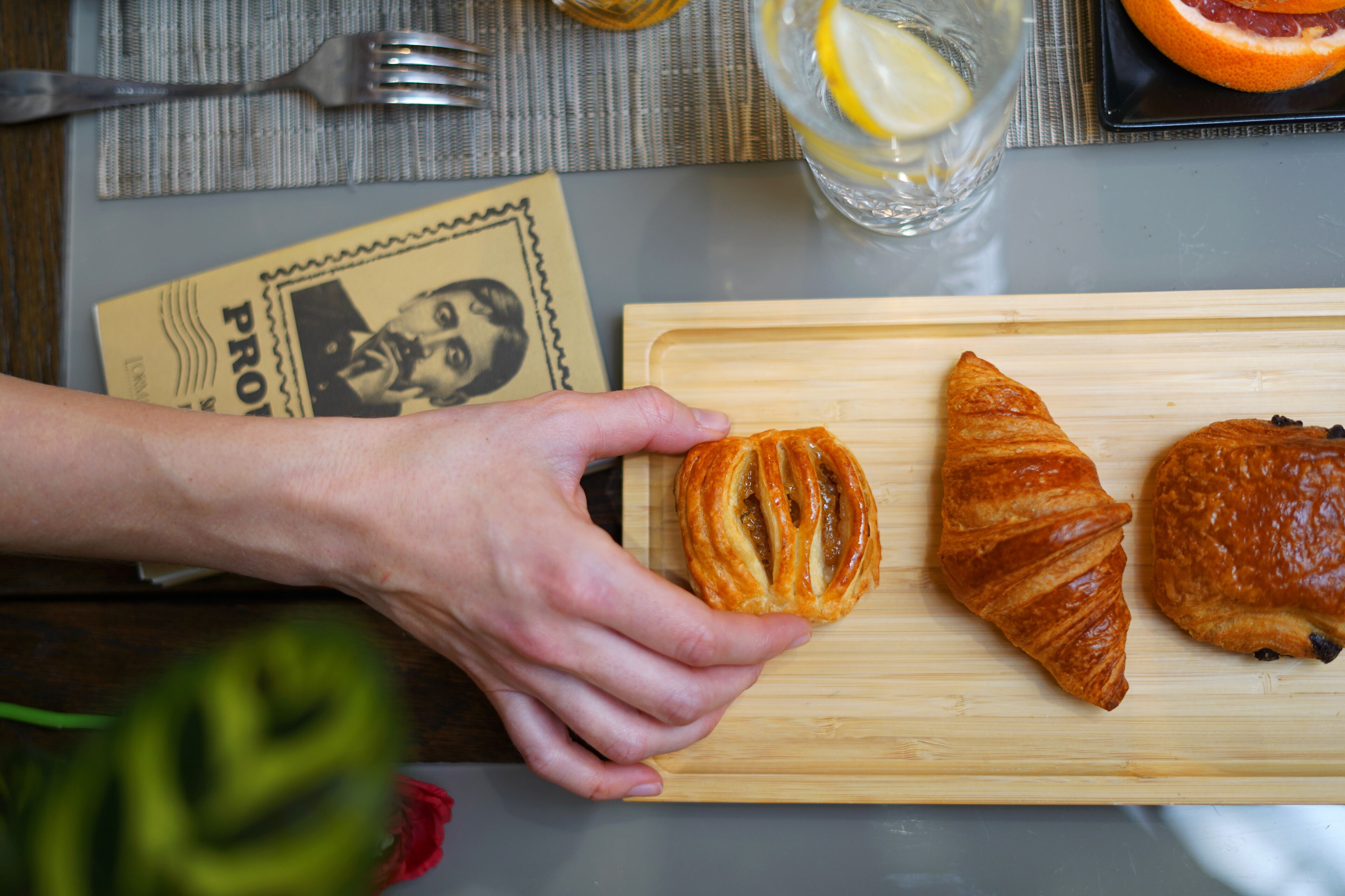 Une planche à découper en bois avec deux croissants et une main qui tend la main pour en prendre un.