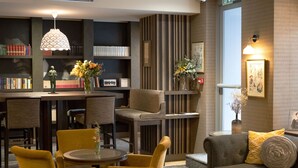A modern interior with a dining area, seating, and a bookshelf. - Hôtel Littéraire le Swann, BW Premier Collection (Paris)