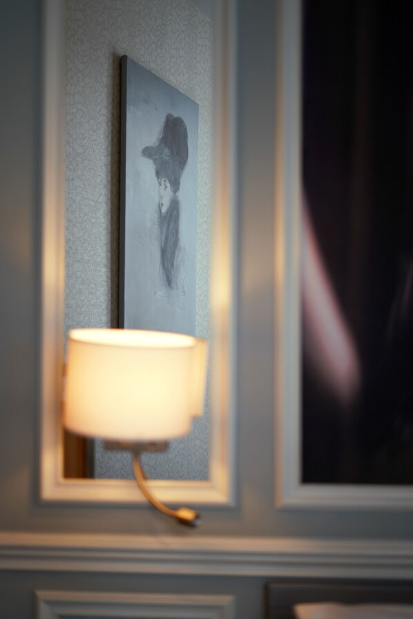 A wall-mounted lamp with a white shade, a framed artwork above it, and a partially visible dark-colored object to the right. - Hôtel Littéraire le Swann, BW Premier Collection (Paris)