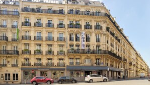 A multi-story hotel with balconies, a sign for 'Hotel Littéraire Le Swann', and parked cars on the street. - Hôtel Littéraire le Swann, BW Premier Collection (Paris)