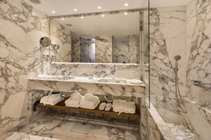 Une salle de bain en marbre avec un lavabo, un miroir et une douche.