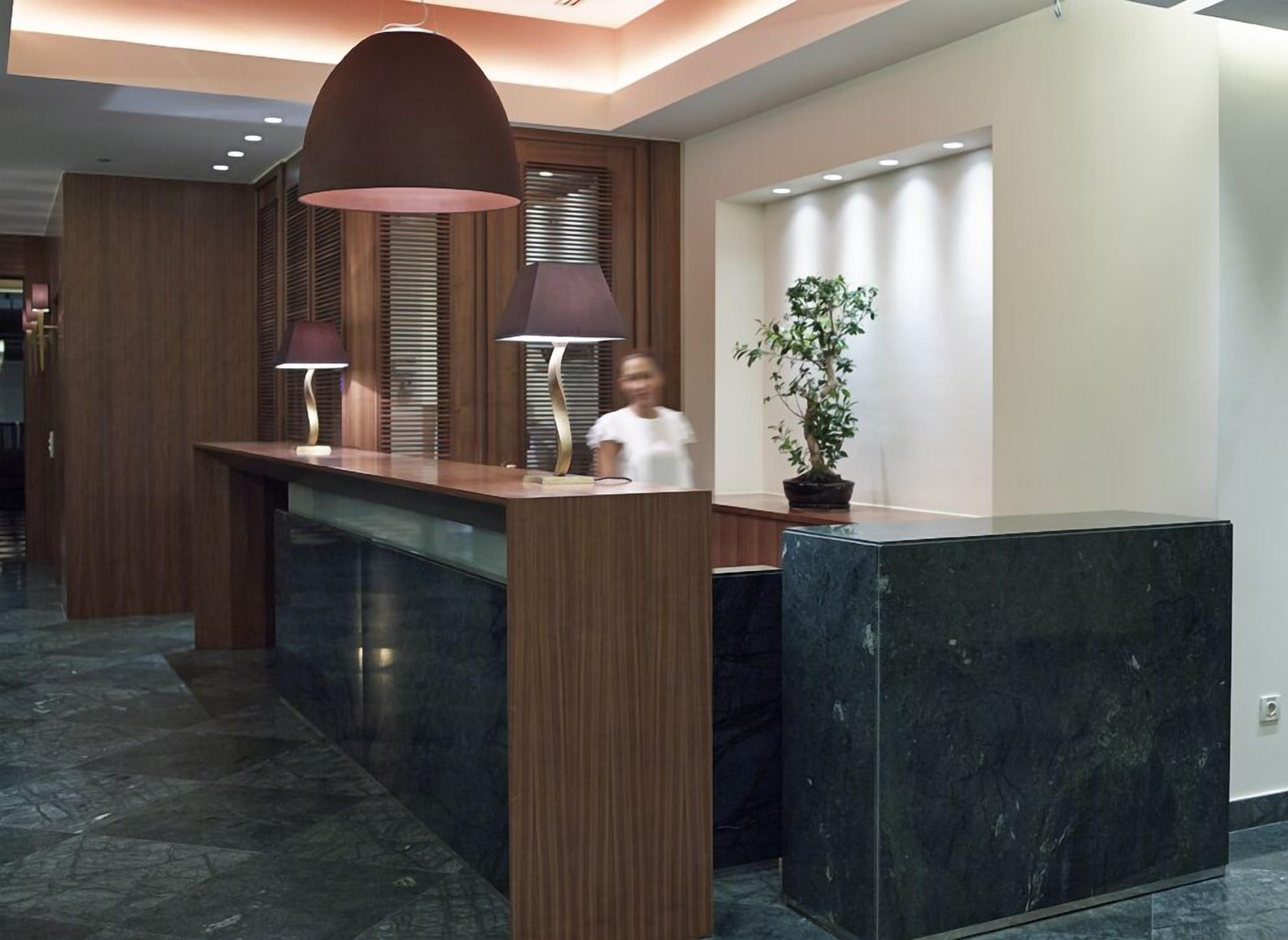 A reception desk with two lamps, a potted plant, and a modern interior design.