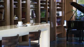 A library with bookshelves, a piano, and a table with chairs.