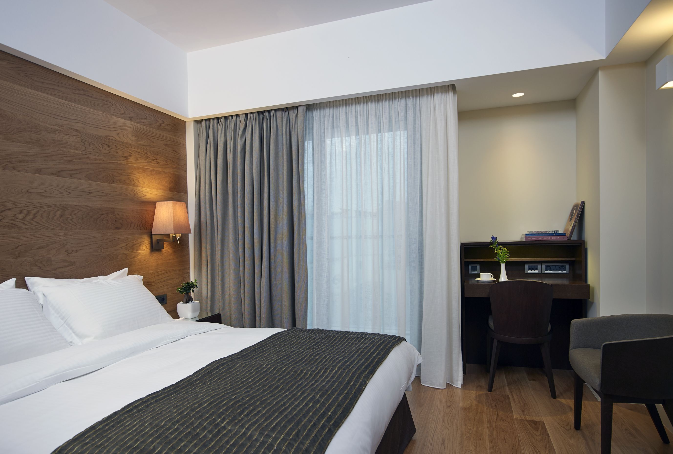 Une chambre d’hôtel avec un grand lit, un bureau et une chaise.