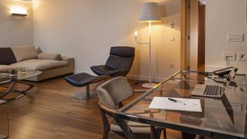 Una sala de estar moderna con una mesa de vidrio, sillas de cuero, un sofá y una lámpara de pie.