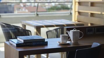 Un balcón con una mesa, sillas, una tetera blanca, una taza y dos libros titulados "From Above and Below".