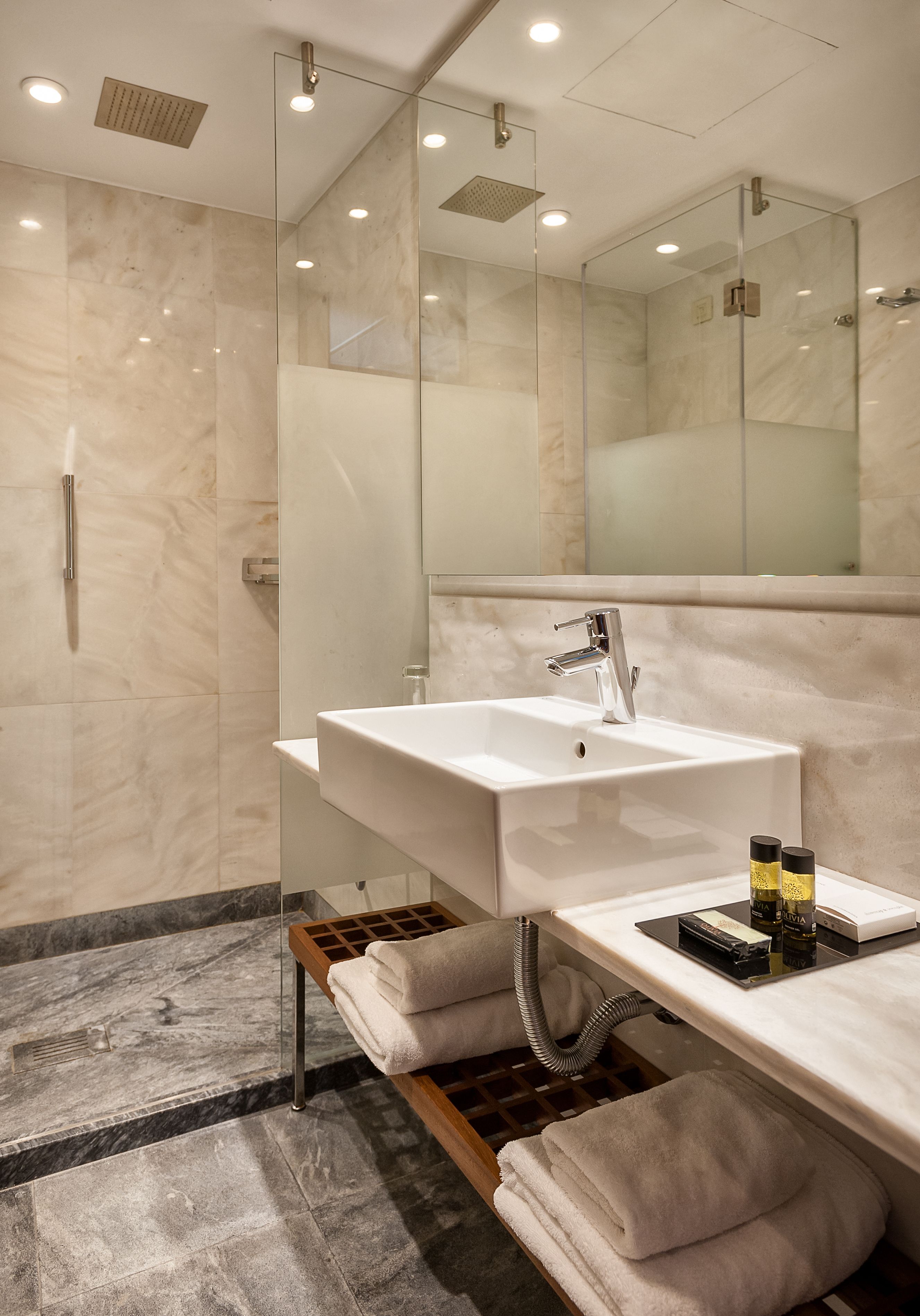 Un baño moderno con ducha de vidrio, un lavamanos espacioso y tocador con perchero.