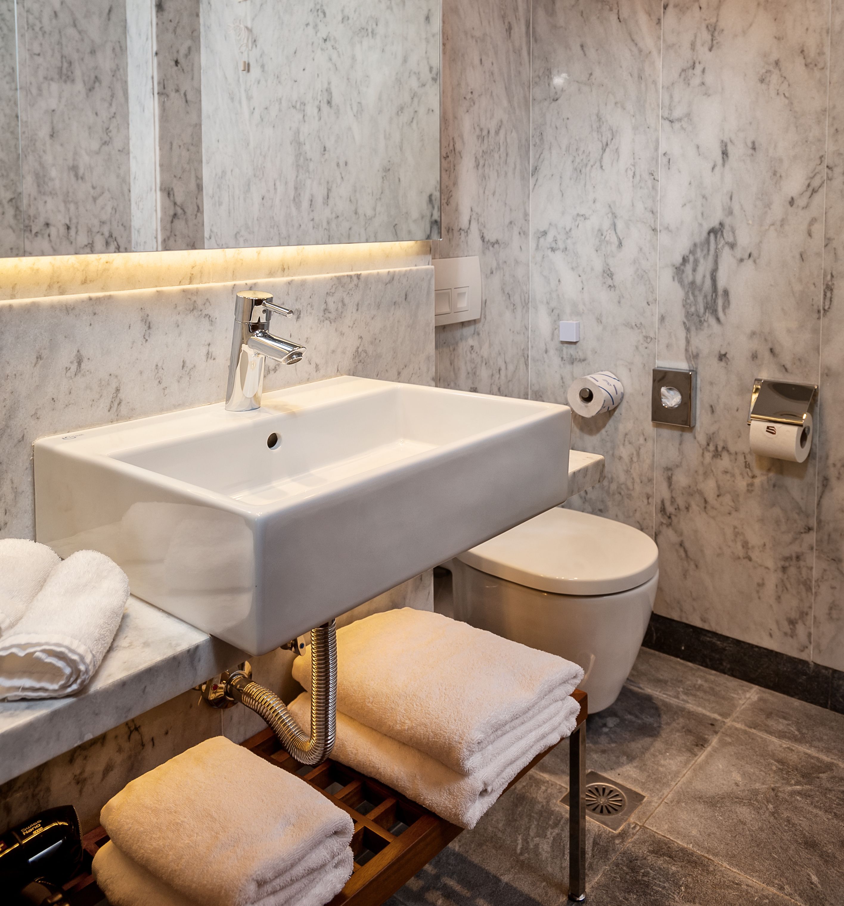 A bathroom with a marble sink, toilet, and towel rack.