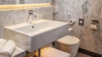 A bathroom with a marble sink, toilet, and towel rack.