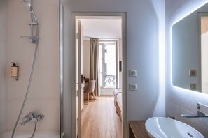 Een moderne badkamer met een douche, wastafel en spiegel.