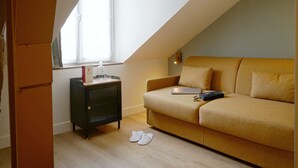 A cozy room with a sofa, a radiator, and a window. - Hôtel Littéraire Arthur Rimbaud, BW Signature Collection (Paris)