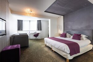 Een moderne hotelkamer met een groot bed, een bureau, een stoel en een televisie.