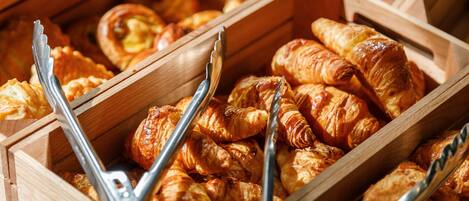 A wooden buffet with various baked goods, including croissants and pastries.