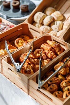 Un bufé de madera con diversos productos horneados, como cruasanes y pasteles.