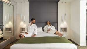 Una habitación de hotel moderna con una cama grande, dos mesitas de noche, un espejo y un armario.