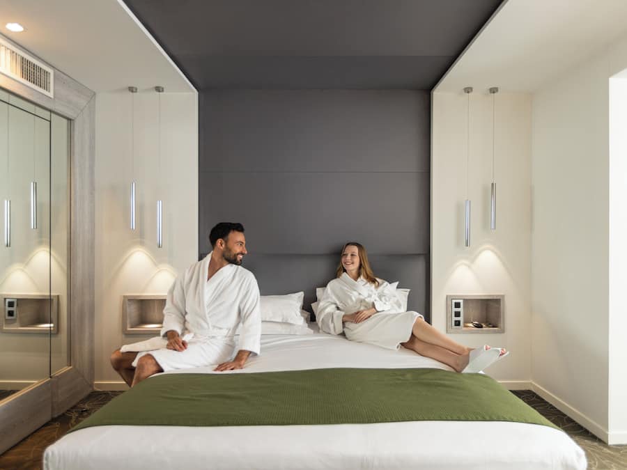Ett modernt hotellrum med en stor säng, två sängbord, en spegel och en garderob.