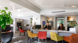 Una recepción moderna con un mostrador, sillas de colores y una gran planta en maceta.