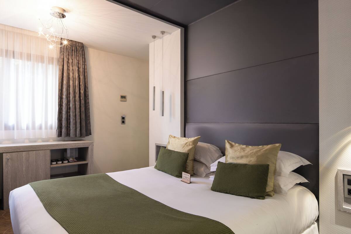 Una habitación de hotel moderna con una cama grande, un escritorio con silla y un armario empotrado.