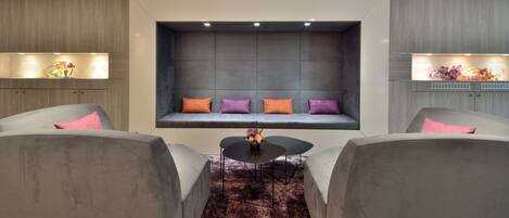 A modern living room with a built-in seating area, a coffee table, and two armchairs.